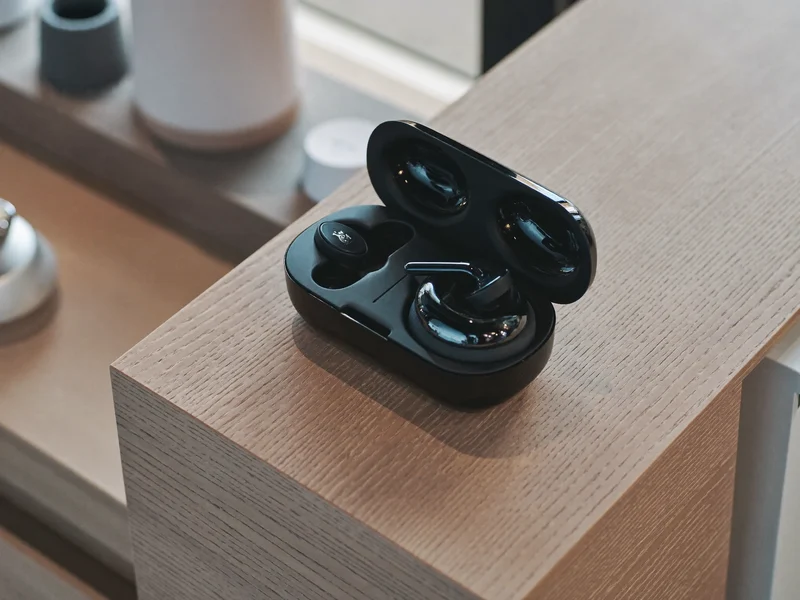 Casque sans fil et écouteurs avec boîtier de charge ouvert sur un comptoir en bois
