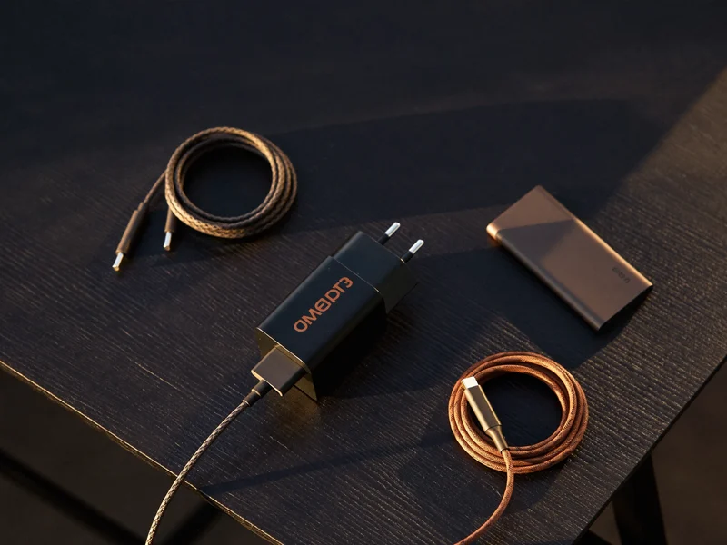 Chargeur mural, câbles tressés USB-C et batterie externe posés sur un établi sombre
